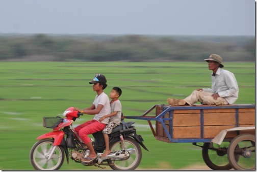Motorcycle and unorthodox passenger speeding down the road in Cambodia